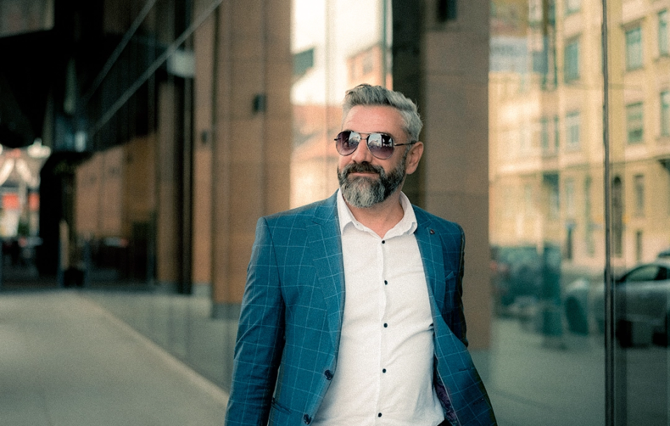 older professional gentleman in blazer glasses walking near office building 
