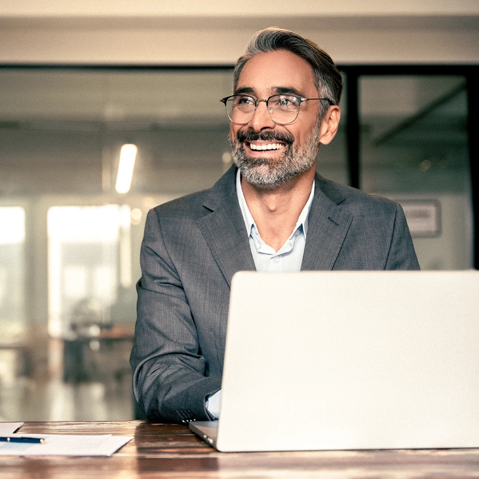 mature latin man with his laptop in an office smiling