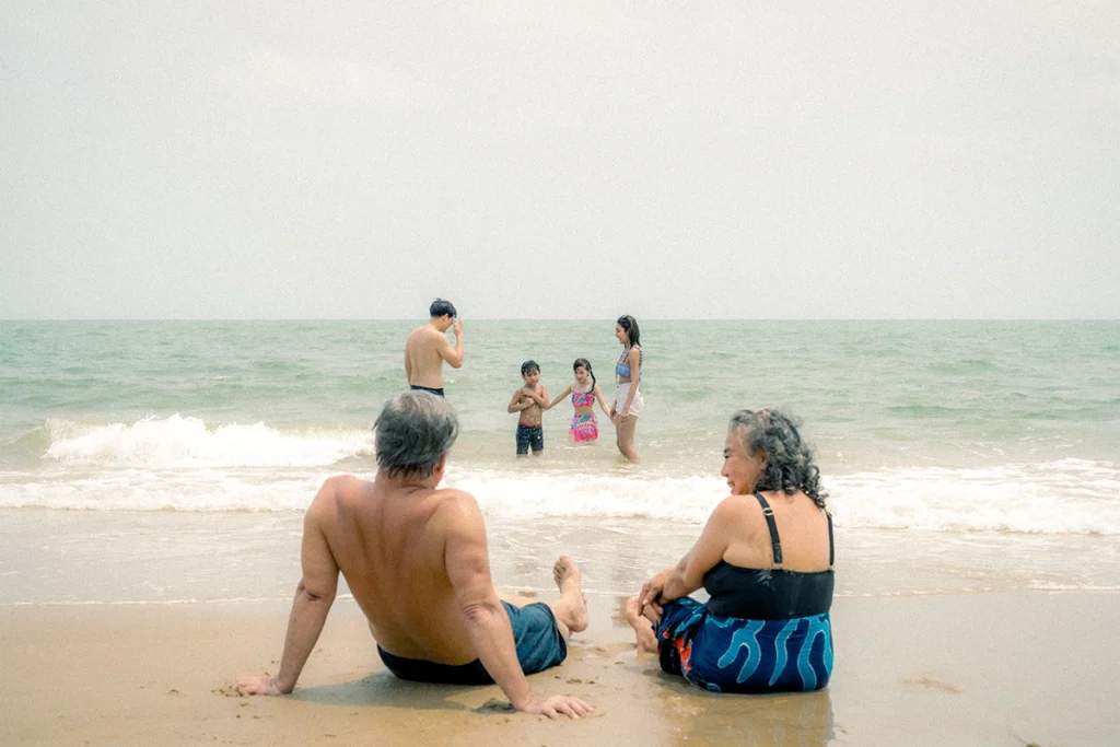 multi-generational family sitting on the beach playing in the water on a sunny day