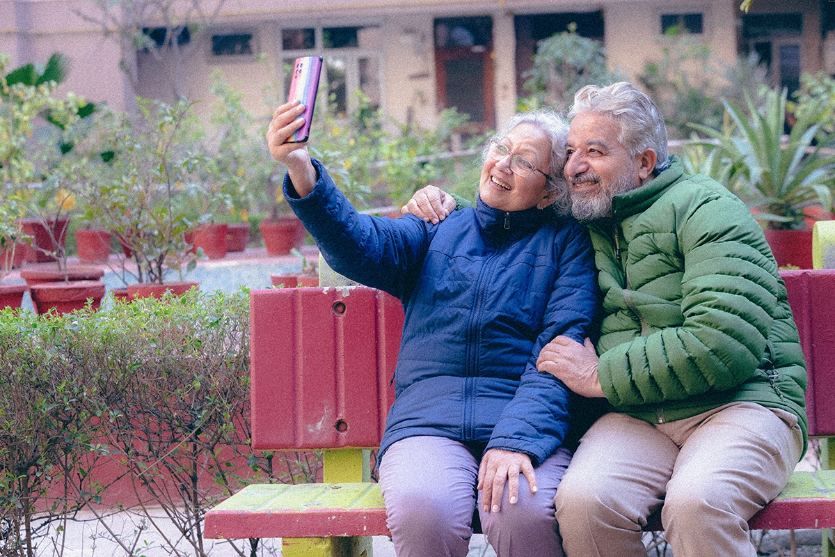 asian_couple_sitting_on_bench_taking_a_selfie_fixed_annuity_index_retirement_solutions copy