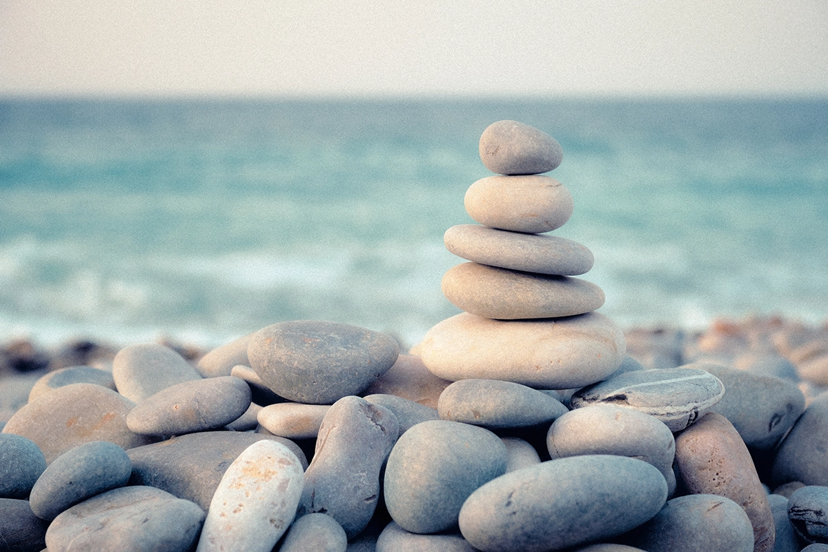 stacked-zen-rocks-on-the-beach-market-value-adjustment stacked zen rocks on the beach with a blurred viewed of the ocean