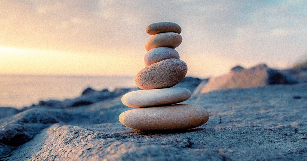 stones pyramid on the seashore at sunset