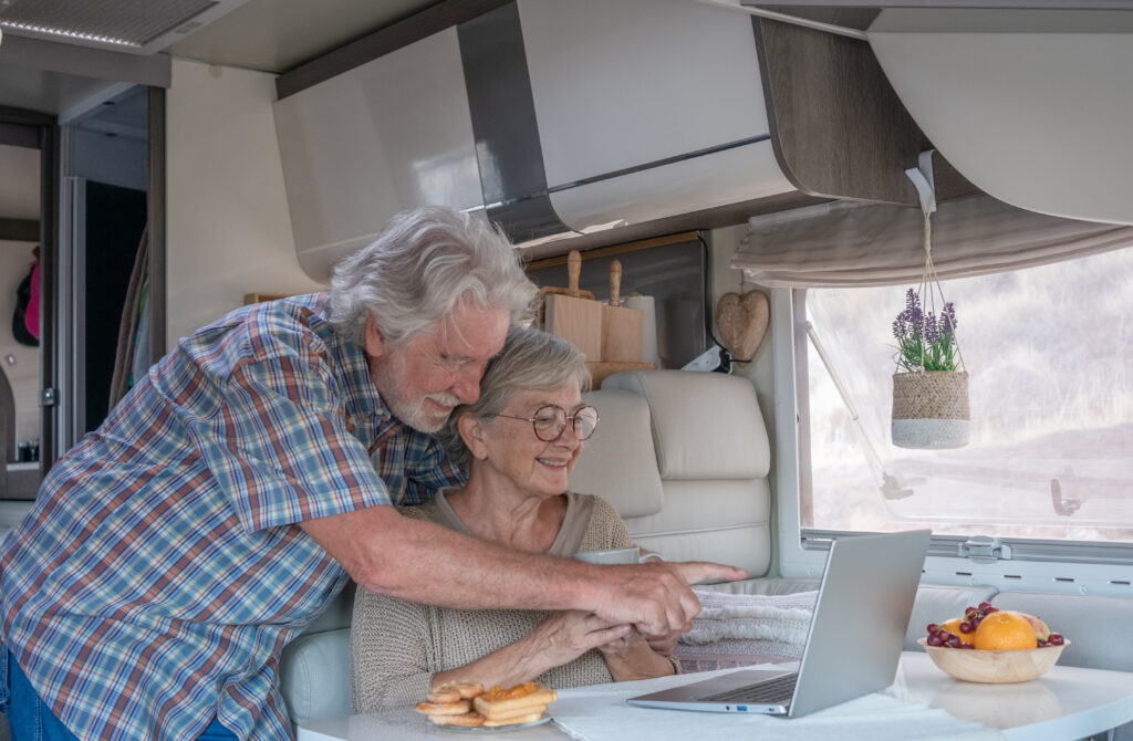 Smiling senior couple in travel vacation leisure sitting inside a camper van enjoying breakfast together. Caucasian elderly people and retirement lifestyle