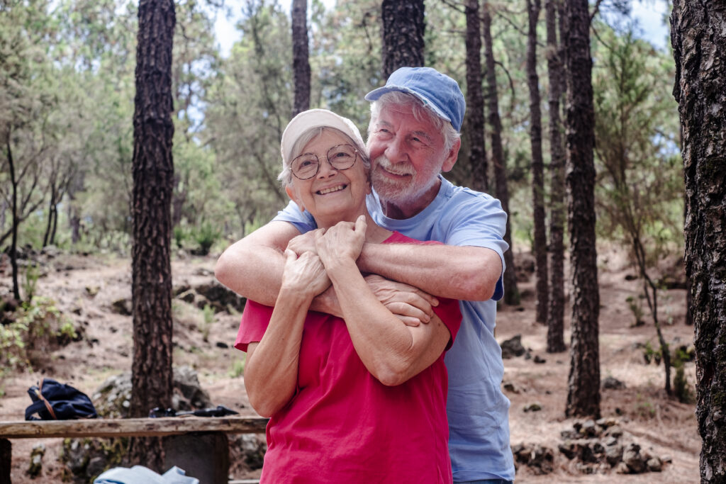 Happy senior couple hugging enjoying mountain hike in the woods 